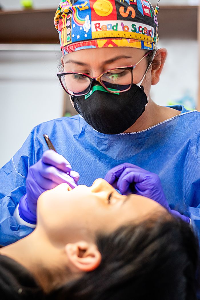services-03 A dentist wearing colorful cap and mask treats a patient, focusing on dental care.