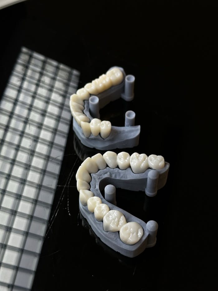 services-02 High-quality 3D printed dental molds displayed on a reflective dark background, showcasing dental technology.